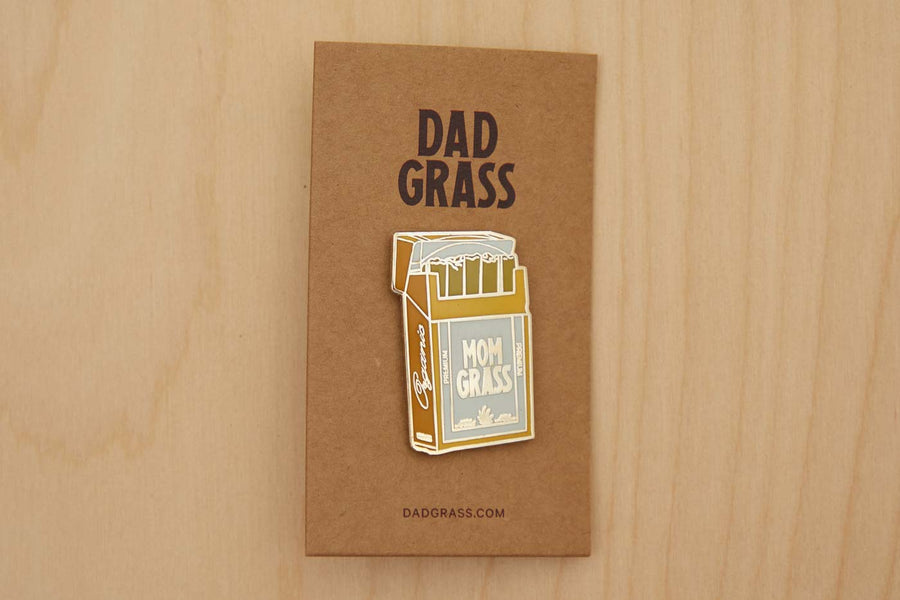 Mom Grass Pack Pin on cardboard on a wooden table