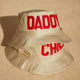 Dad Grass Pride 2021 tan bucket hat. Top hat shows 'DADDY' side, bottom hat shows "Chill" side.