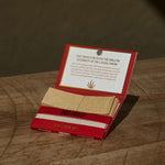 Rolling paper with filter tips in a Dad Grass red pack on a wooden surface