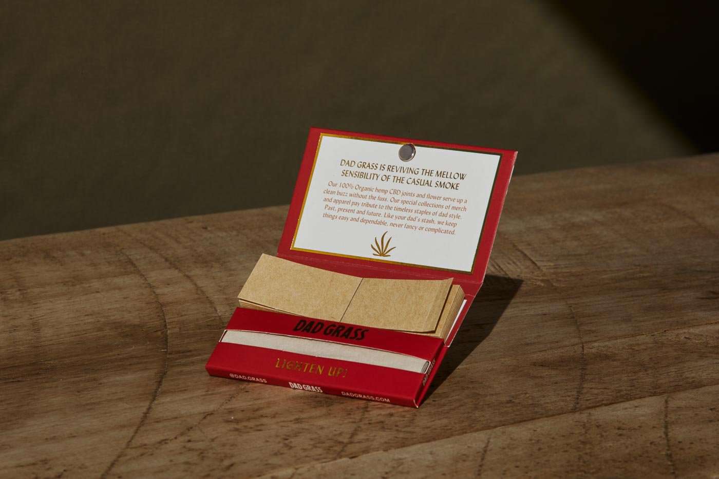 Rolling paper with filter tips in a Dad Grass red pack on a wooden surface