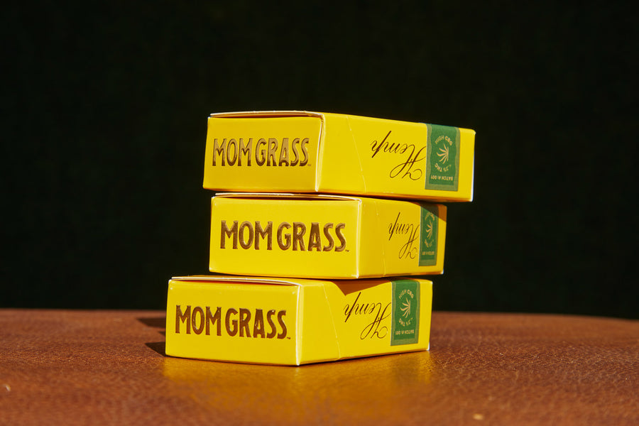 Three boxes of Mom Grass CBG prerolls stacked on top of each other