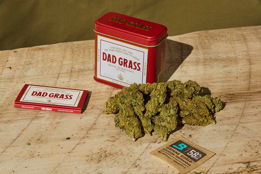Dad Grass CBD Hemp Flower In A Red And On The Table With Rolling Papers