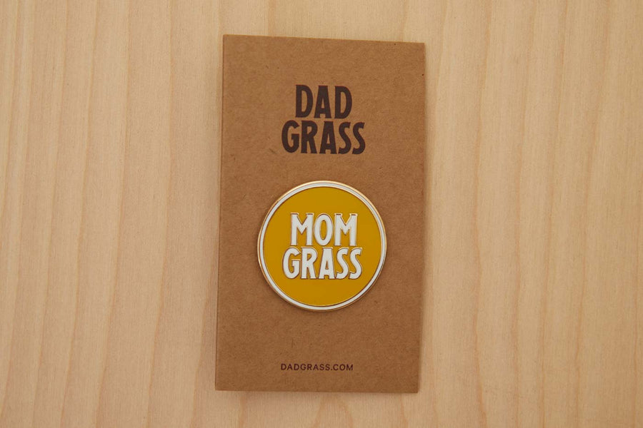 Mom Grass Circle Pin on cardboard on a wooden table