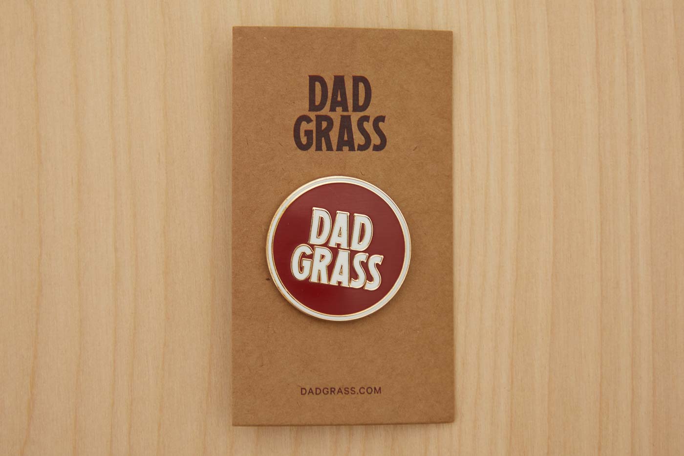 Dad Grass Circle Pin on cardboard on a wooden table