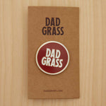 Dad Grass Circle Pin on cardboard on a wooden table