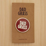 Dad Grass Circle Pin on cardboard on a wooden table