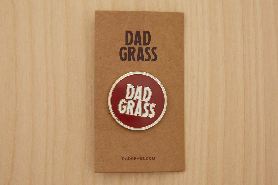Dad Grass Circle Pin on cardboard on a wooden table