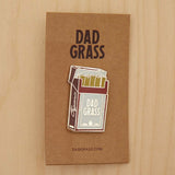 Dad Grass Pack Pin on cardboard on a wooden table