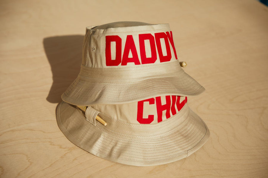 Dad Grass Pride 2021 tan bucket hat. Top hat shows 'DADDY' side, bottom hat shows "Chill" side.