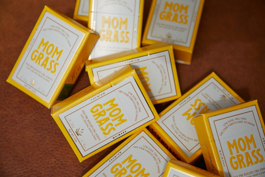 Boxes of Mom Grass CBG prerolls lying on a table