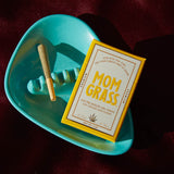 Mom Grass CBG pre rolled hemp joint in ashtray next to Mom Grass CBG 5-pack box