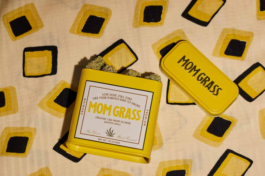 Yellow Mom Grass CBG Hemp Flower Tin On A Yellow Cloth