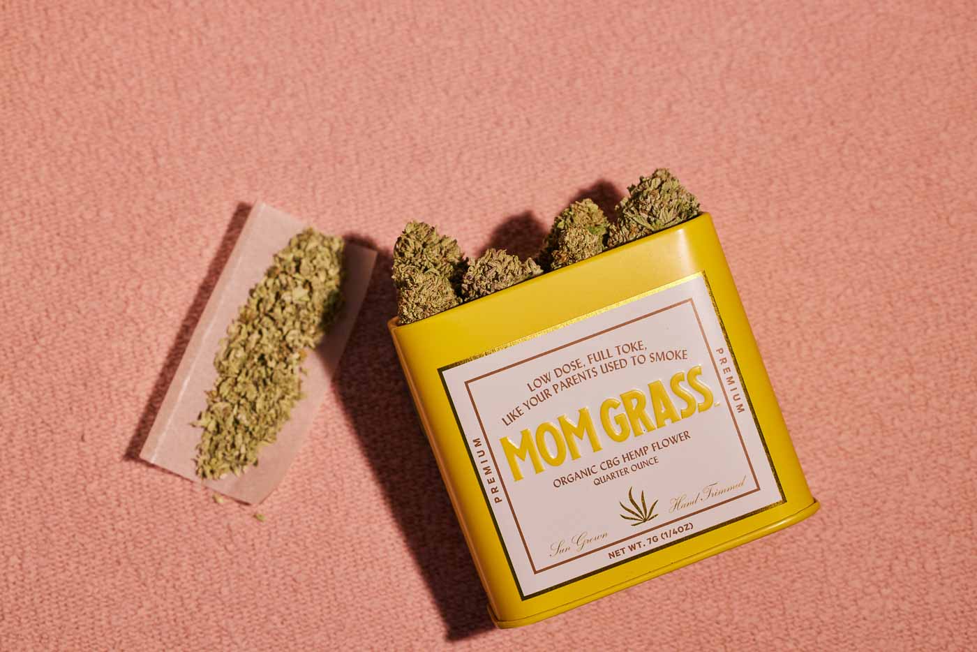 CBG Hemp Flower Coming Out From A Yellow Tin With Crushed CBG On A Rolling Paper