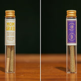 Mom Grass hemp CBG 2 prerolls  in a glass vial next to back side of the same