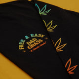 Unisex Black LS Tee With Dad Grass x Free & Easy And Hemp Leaves Printed On It Folded Close Up